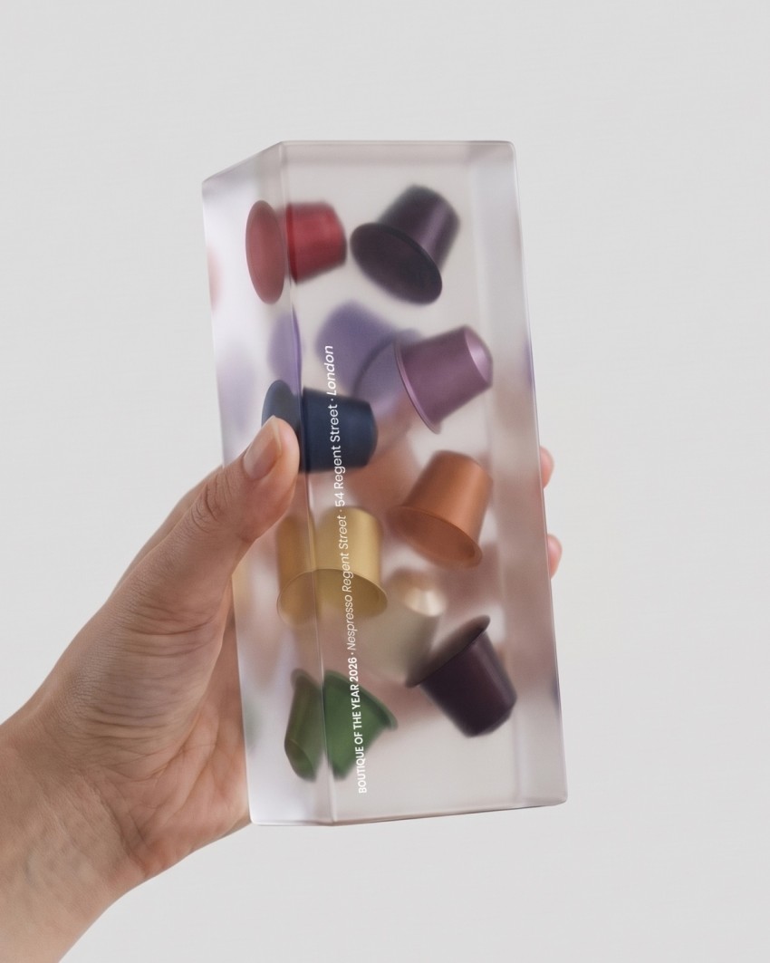 Nespresso-Trophäe, 2026 - Einschluss in Acrylglas, in der Hand gehalten
